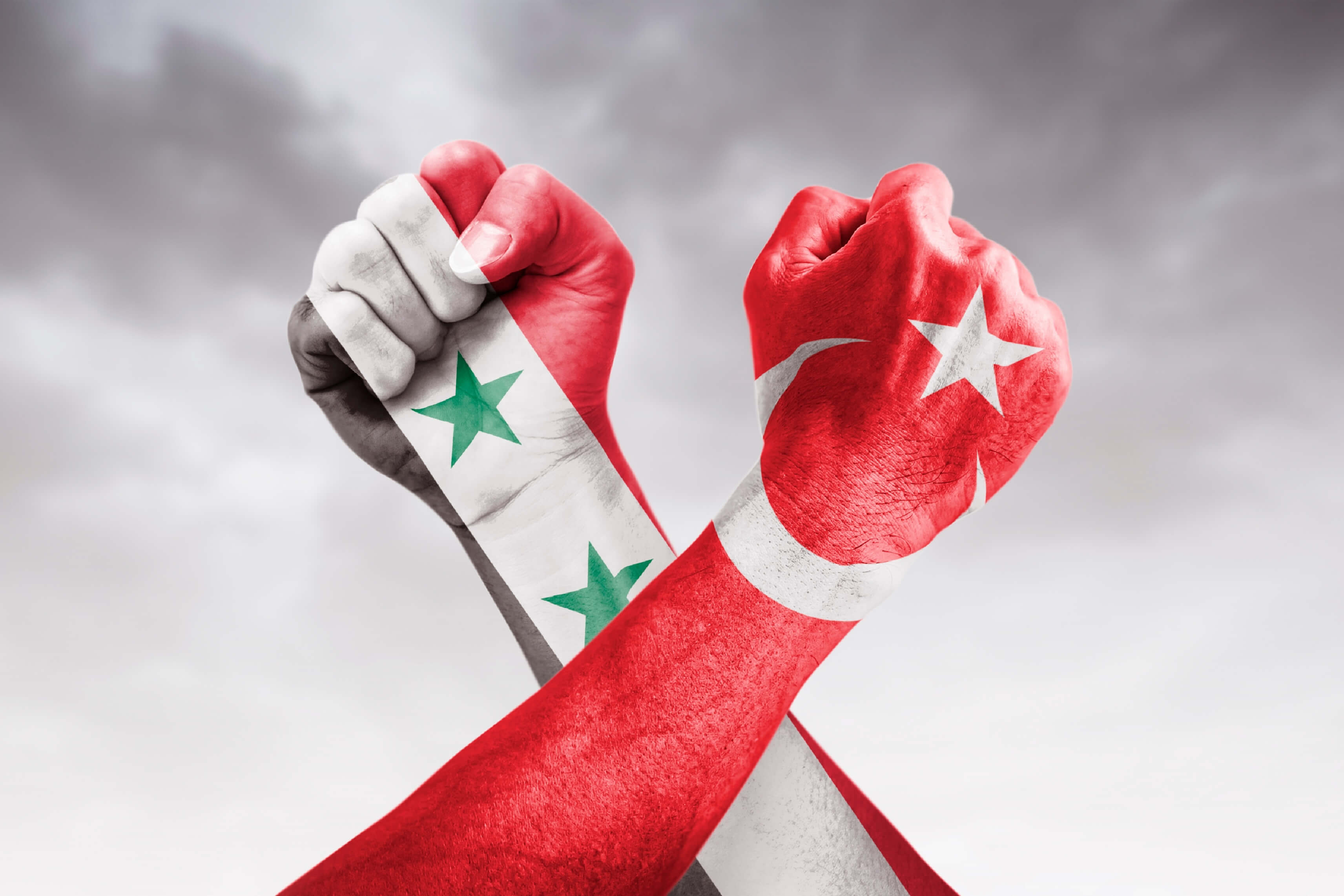 Flags of Turkey and Syria painted on two clenched cross-fists on black background / tense relationship between Turkey and Syria concept